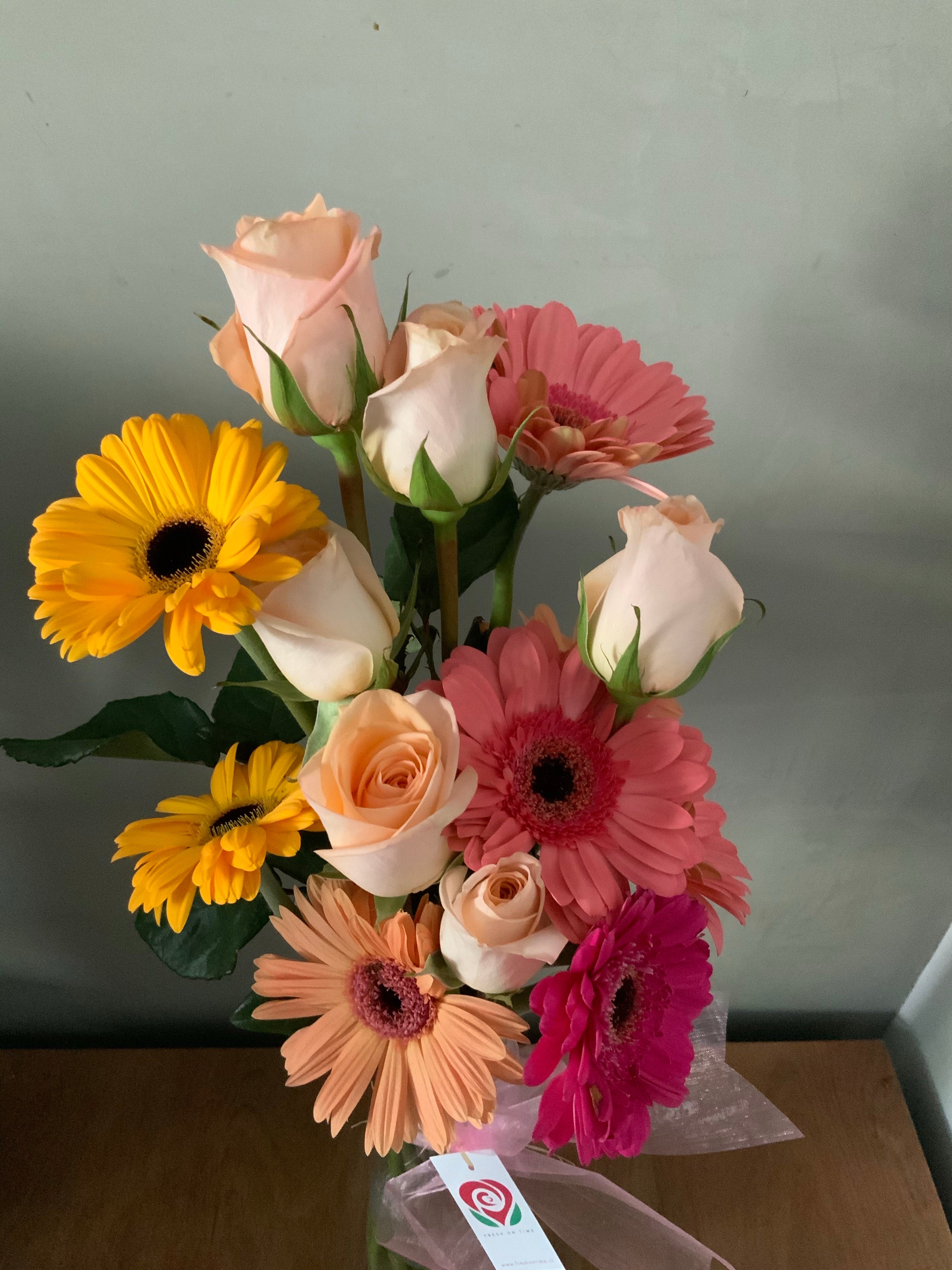 Florero de vidrio con rosas y gerberas